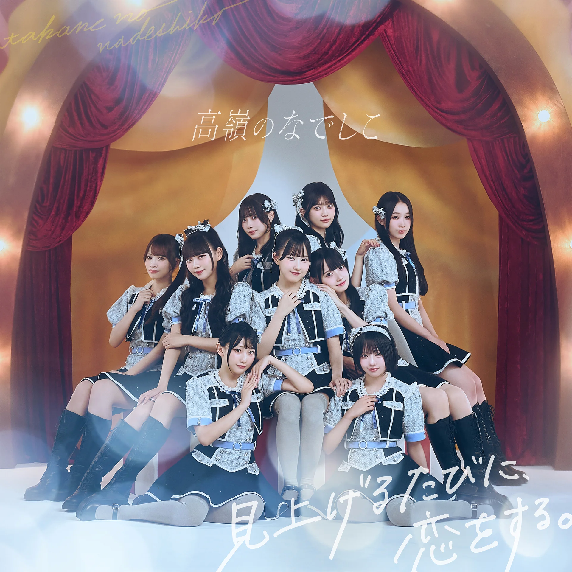 Skupina izvajalk v ujemajočih se kostumih na rdeči sceni z japonskim besedilom