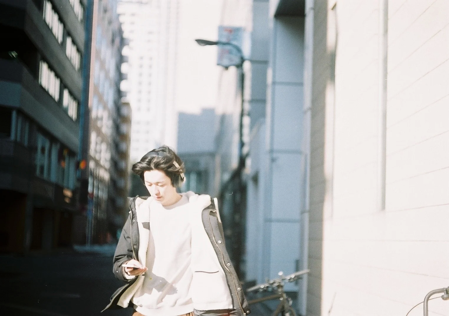 Ýagty şäher arçasynda telefonyny göterip, jaket geýän adam ýöreýär.