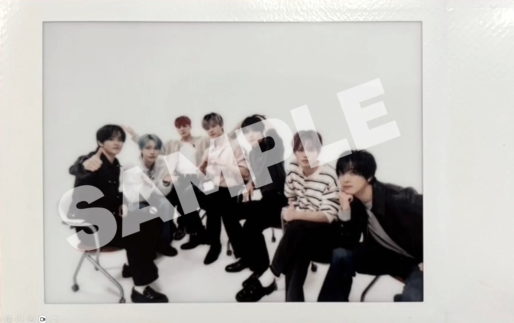 Syv personer som sitter på rekke på stoler, med teksten SAMPLE som overlegg