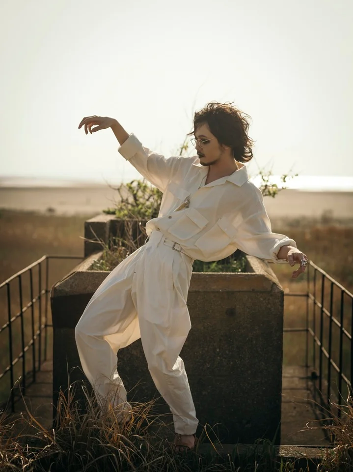 Person in a white outfit posing outdoors on a concrete structure