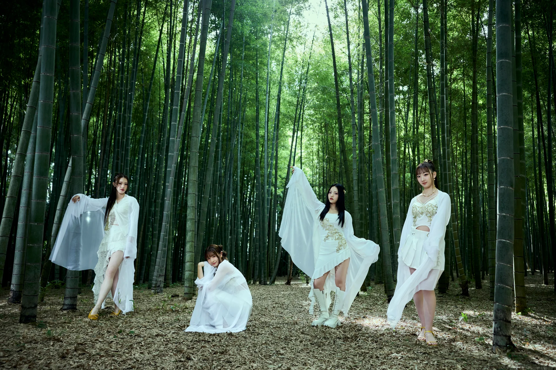 Четири жени во елегантни бели тоалети позираат во бамбусова шума