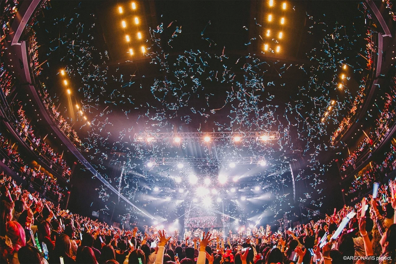 Scène de concert avec des lumières vives et des confettis tombant sur le public, prise lors de l