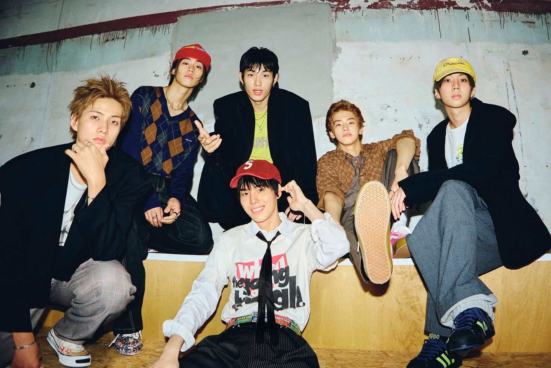 Anim na kabataang lalaki na nakapose nang casual, nakasuot ng mga trendy na kaswal na damit sa isang urban na kapaligiran.