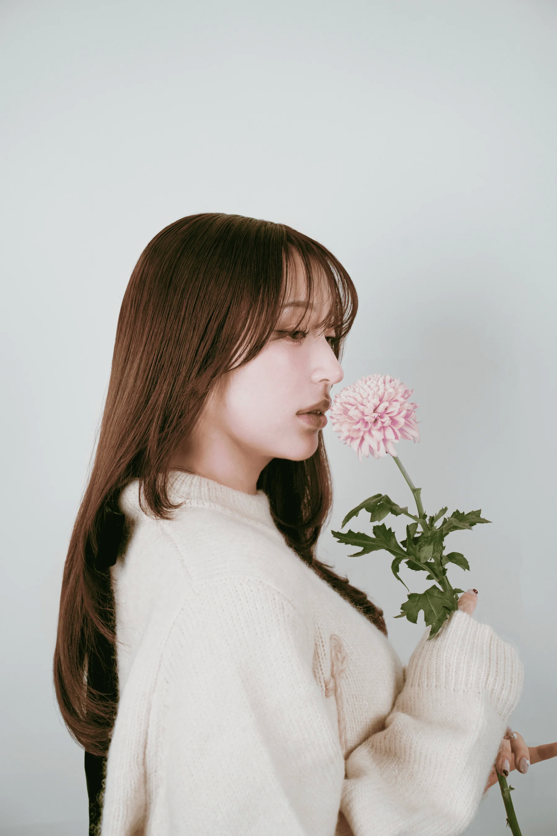 Mahiru držeći ružičasti zinnia cvet u profilu