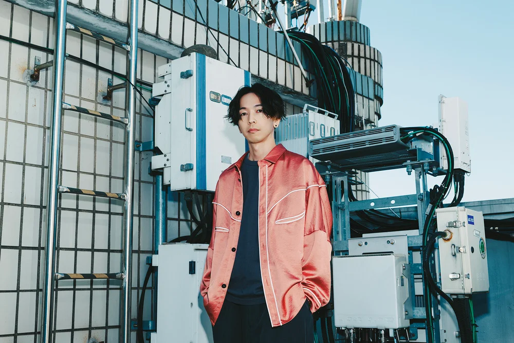 Person in a pink jacket standing in an industrial setting with equipment and blue sky
