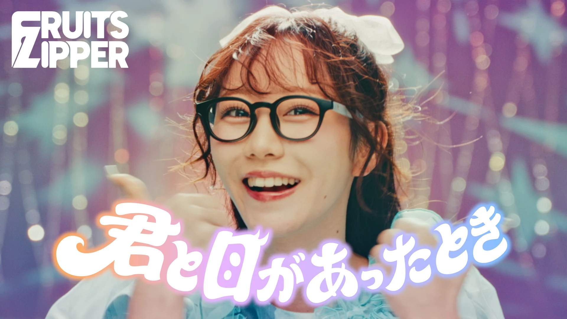 Uśmiechnięta kobieta w okularach i kokardą, kolorowy tekst po japońsku i logo <a href="https://onlyhit.us/music/artist/FRUITS%20ZIPPER" target="_blank">FRUITS ZIPPER</a>