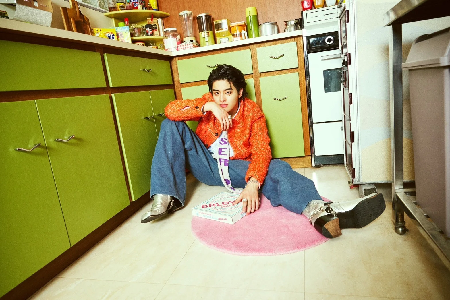 ISSEI сидит на кухонном полу, держа коробку из-под пиццы