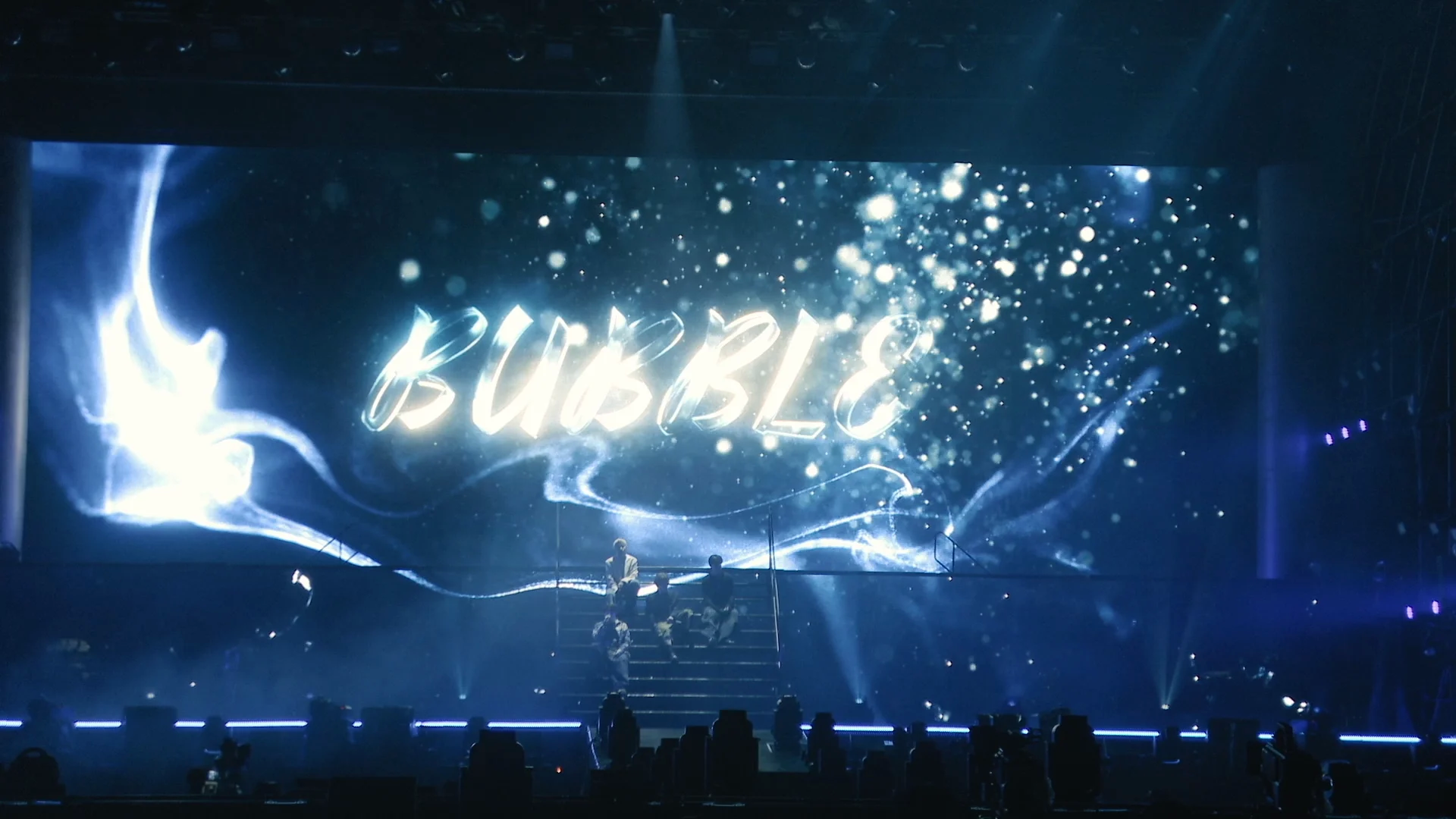 BUBBLE illuminated on concert stage with performer silhouettes