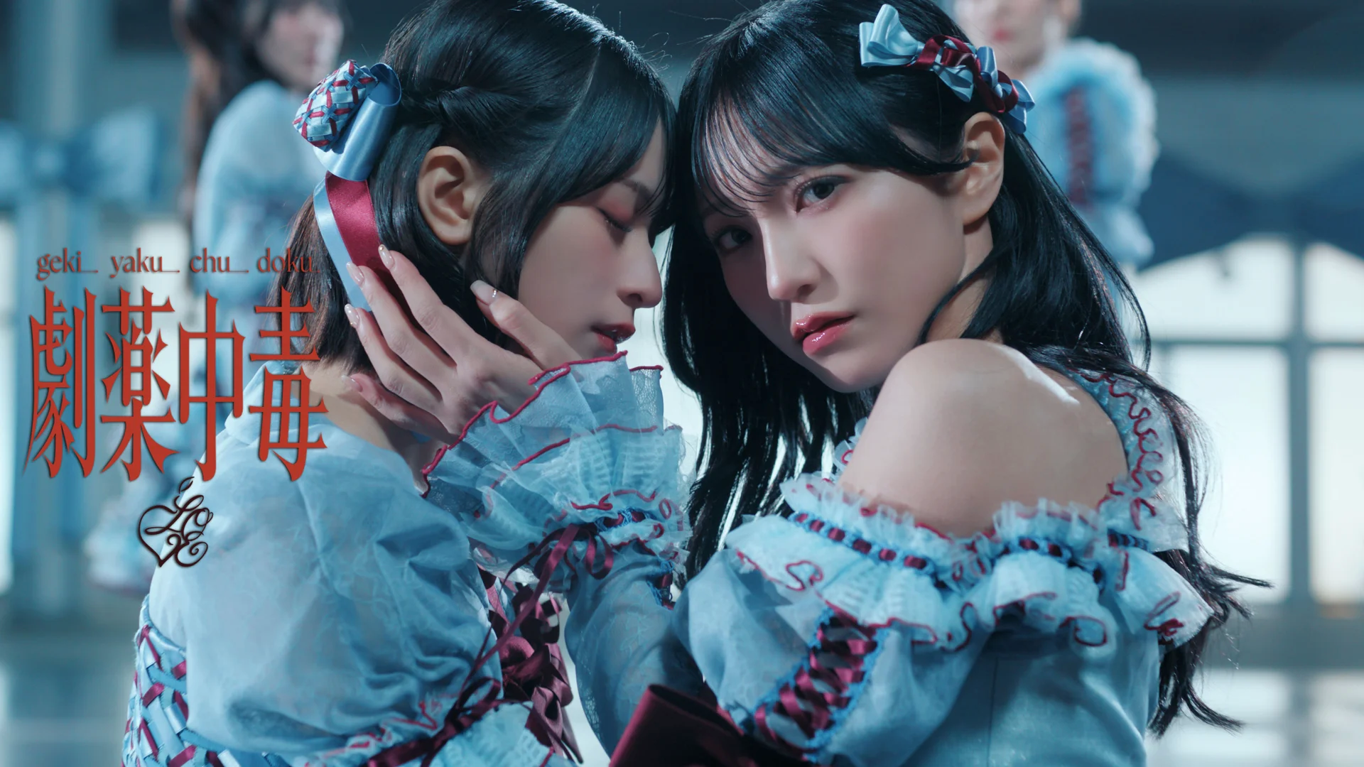 Twa leden fan =LOVE yn yngeniëuze blauwe en bordeaux klean mei de tekst Gekiyaku Chudoku