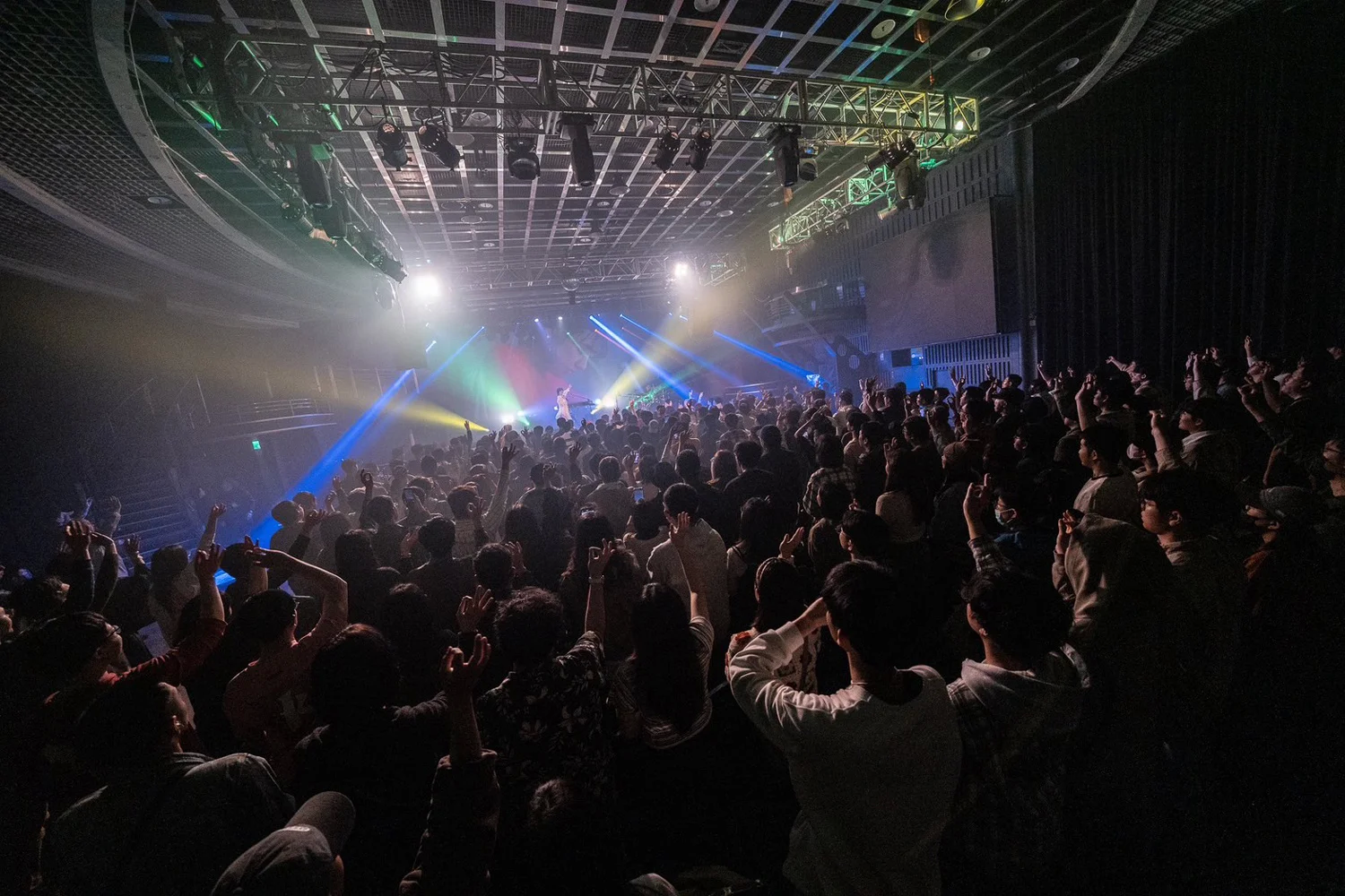 Koncertközönség egy zenei helyszínen színes színpadi fényekkel