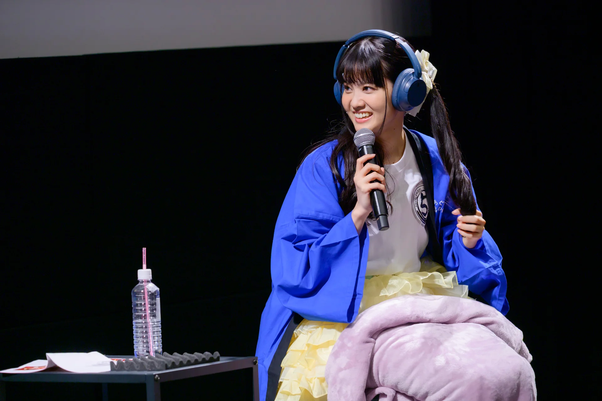 Aguri Onishi yn gwrando ar demos gyda chlustffonau yn y digwyddiad