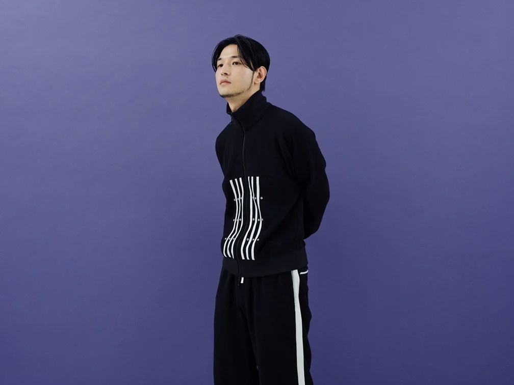 Persona amb vestit negre sobre un fons llis morat