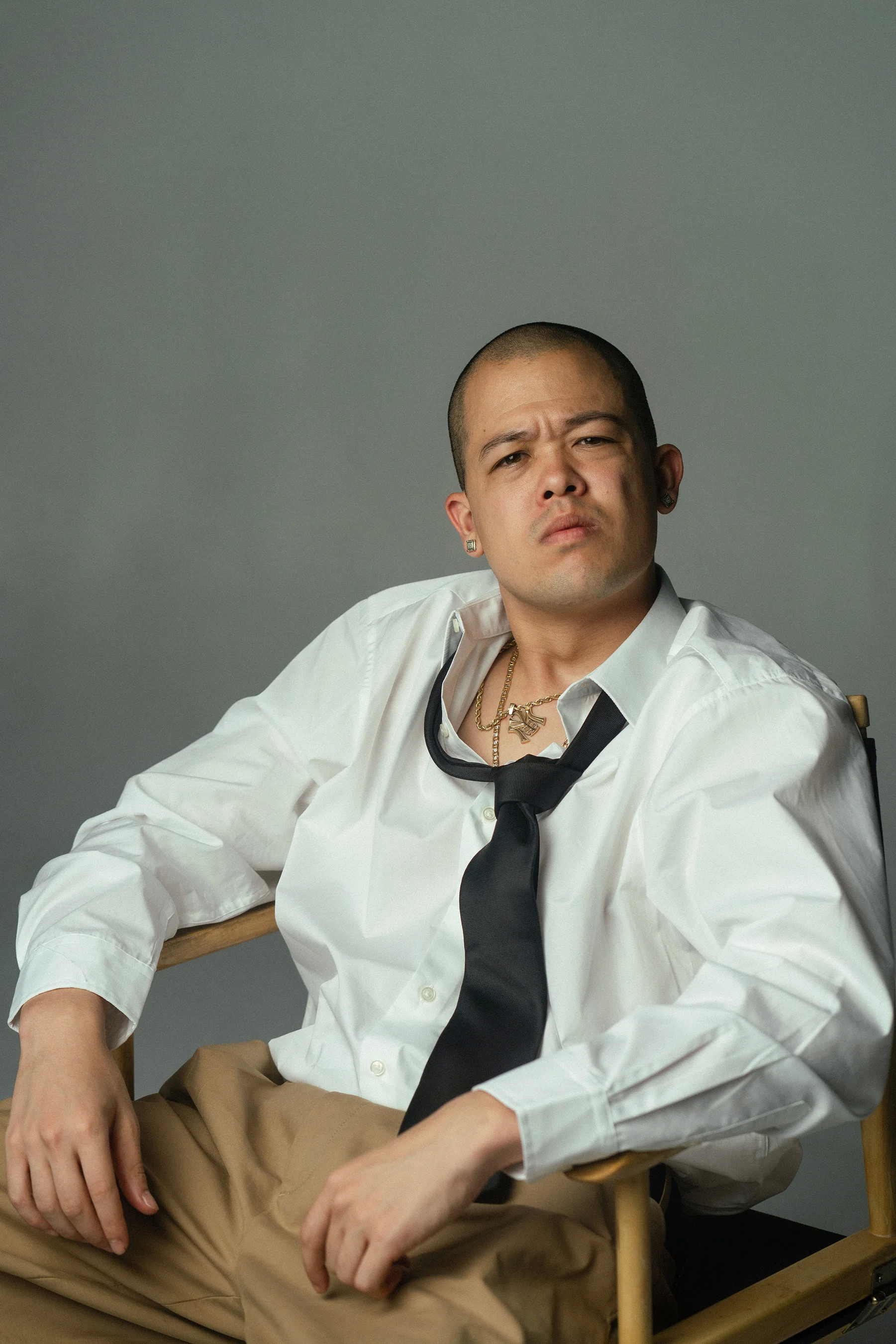 MIYACHI sitting in a chair wearing a white shirt and black tie