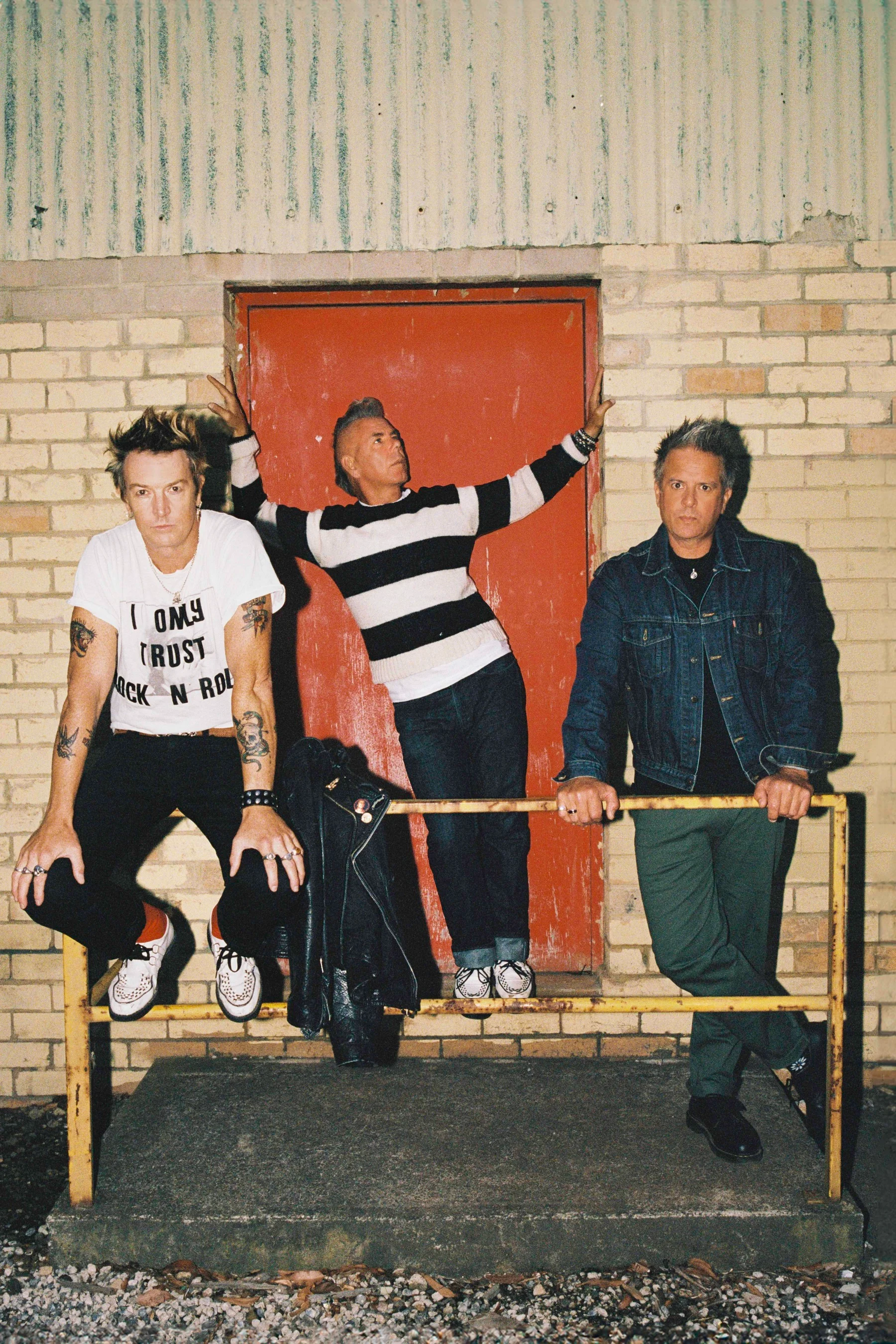 The Living End band members posing against a brick wall