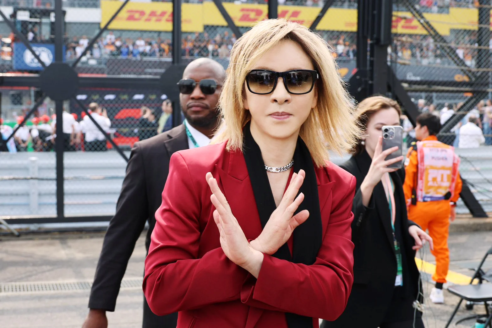 YOSHIKI в красной куртке делает жест X на мероприятии F1