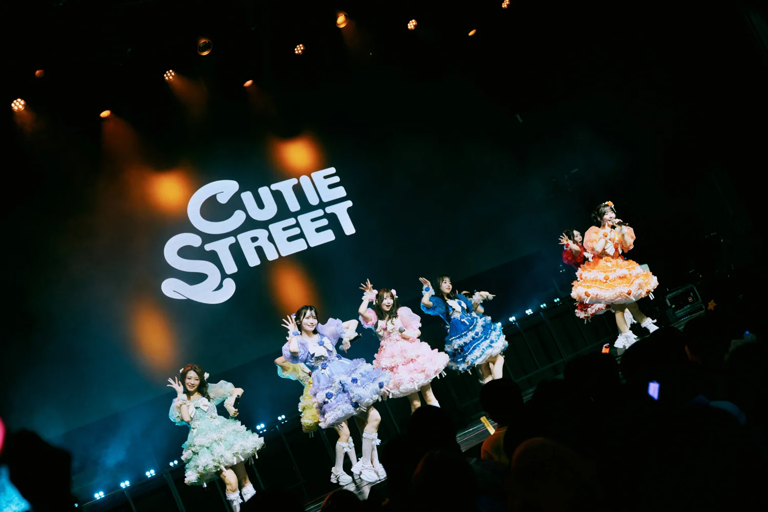 CUTIE STREET performers on stage under a sign