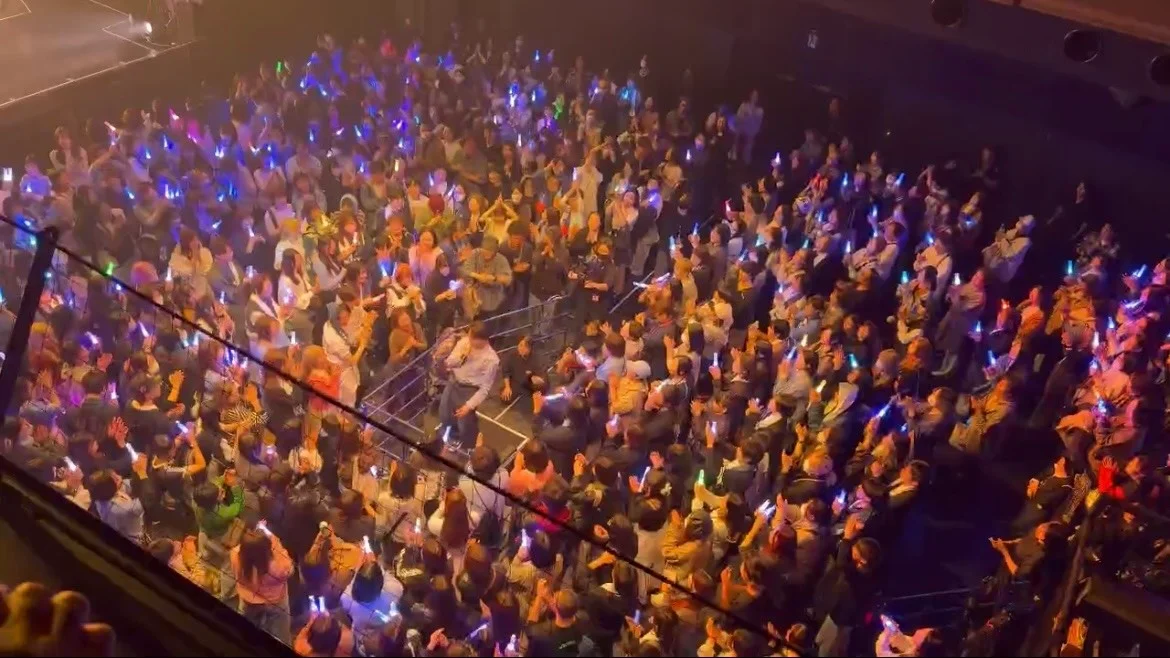 Público en el concierto sosteniendo luces de neón