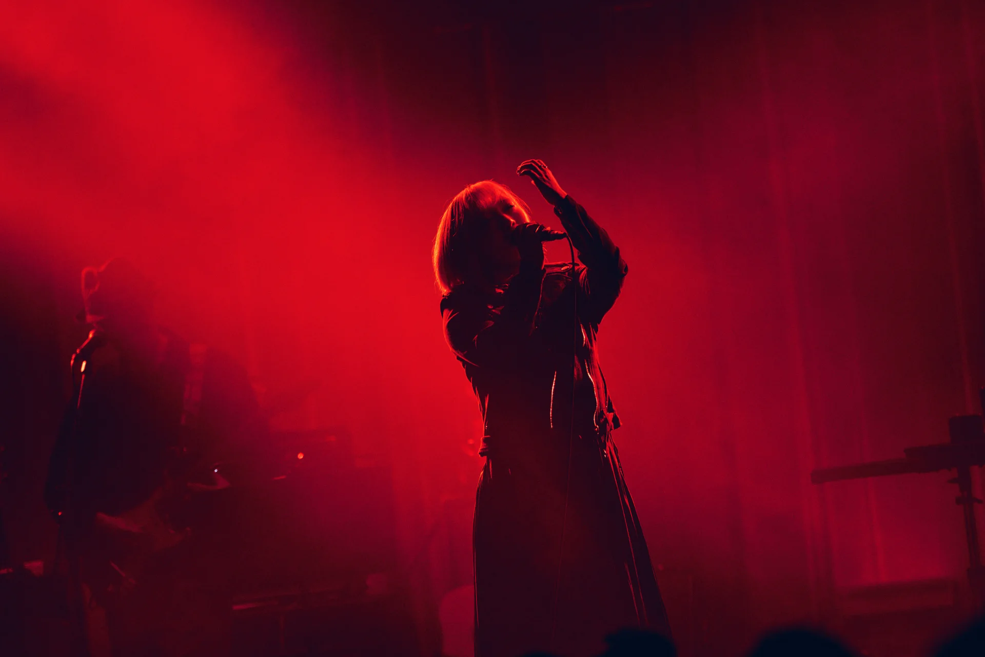 ReoNa vystupujúca na pódiu pod červeným osvetlením