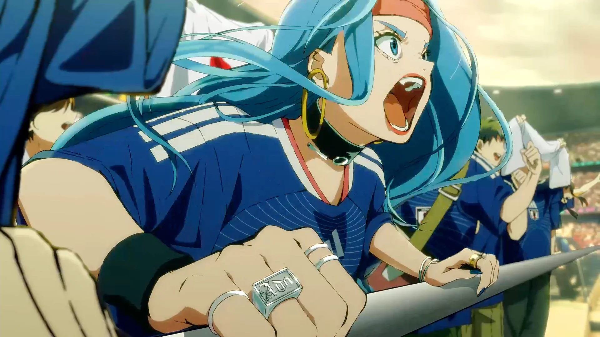 Animacinis personažas su mėlynais plaukais, dėvintis Japonijos futbolo marškinėlius, džiūgia stadione.