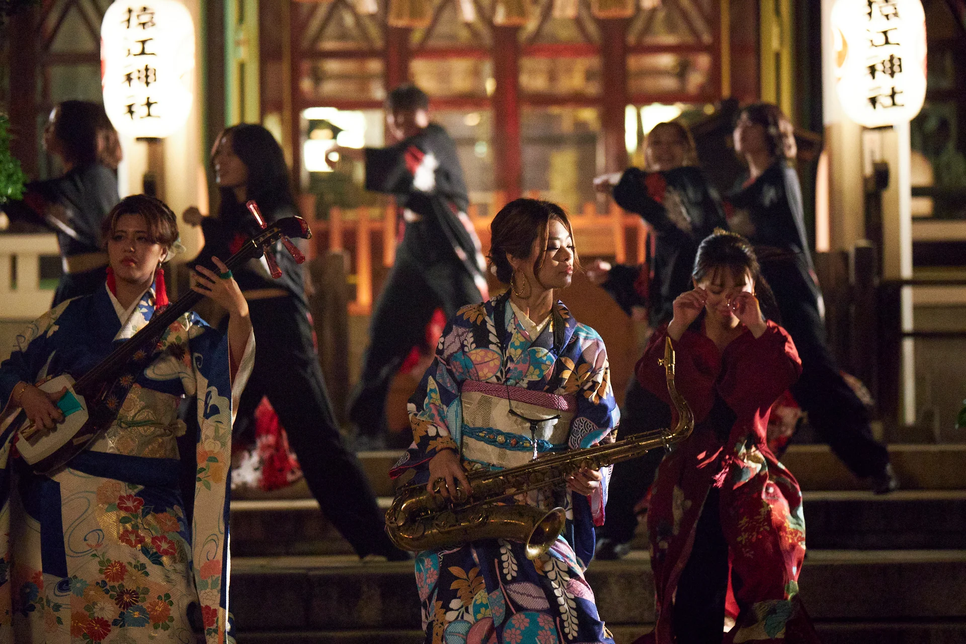 Uitvoerenden in traditionele kledij bij een heiligdom in de nacht