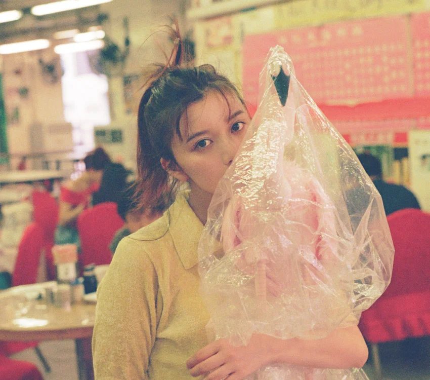 Isang babaeng may hawak na plastic-wrapped flamingo sa loob ng bahay