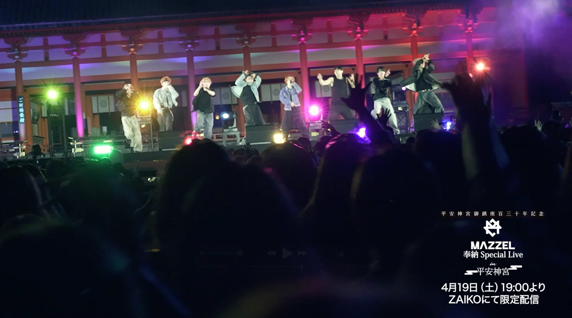 हेइअन श्राइन में रंगीन रोशनी, स्टेज पर एक समूह और दर्शकों के साथ एक लाइव कॉन्सर्ट प्रदर्शन