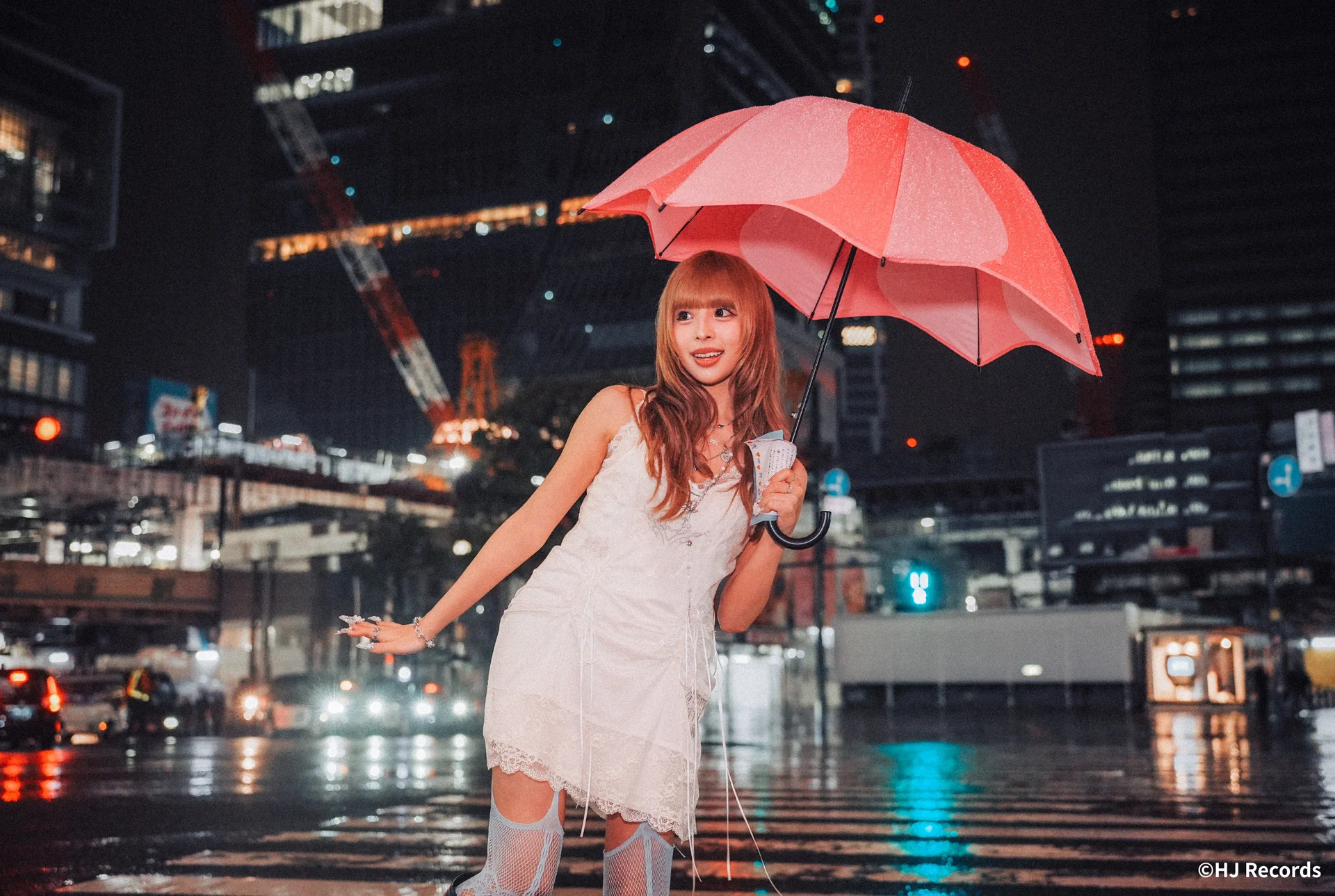 Aisa in a white dress holding a pink umbrella on a rainy street at night