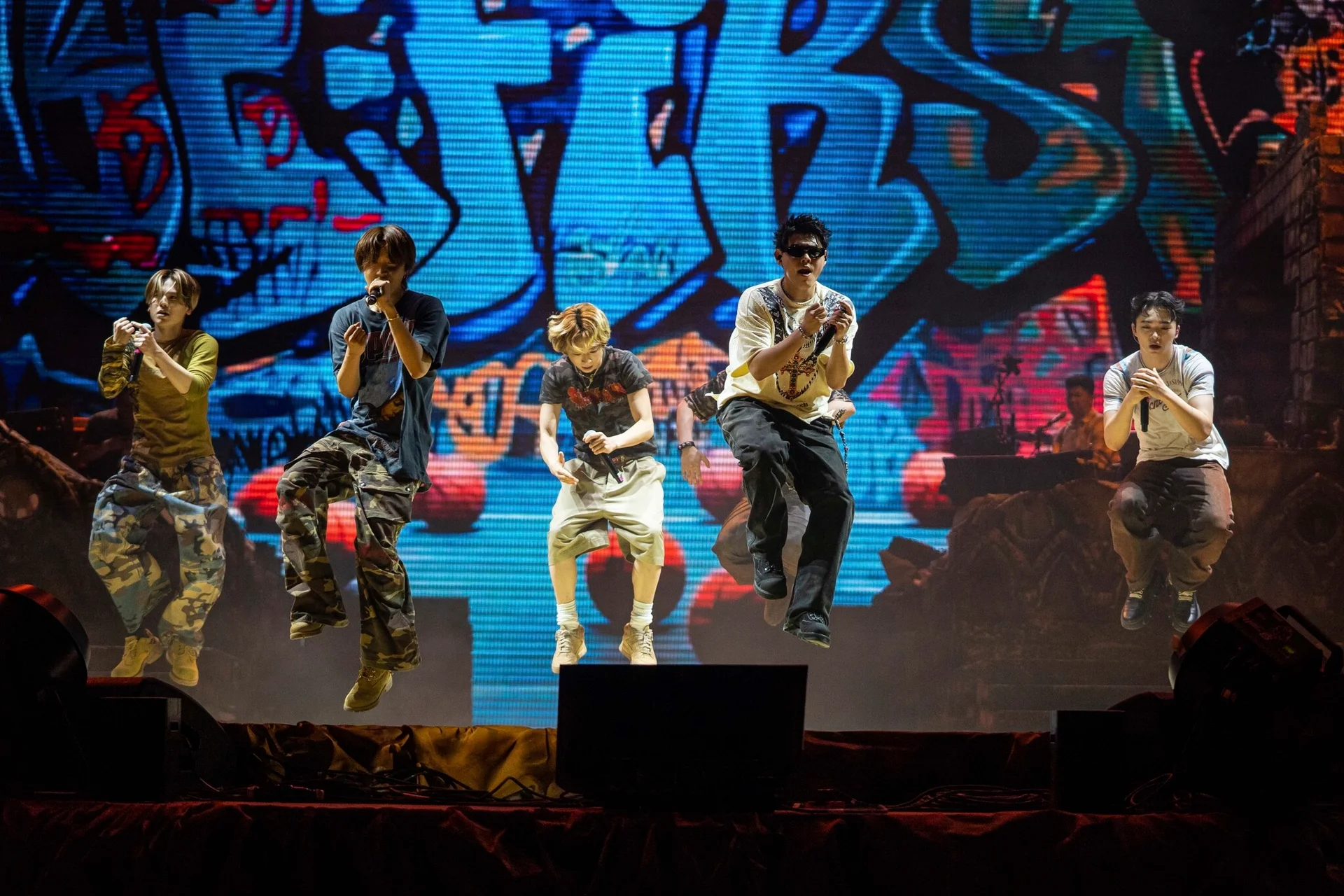 BE:FIRST performing on stage with a graffiti-style backdrop