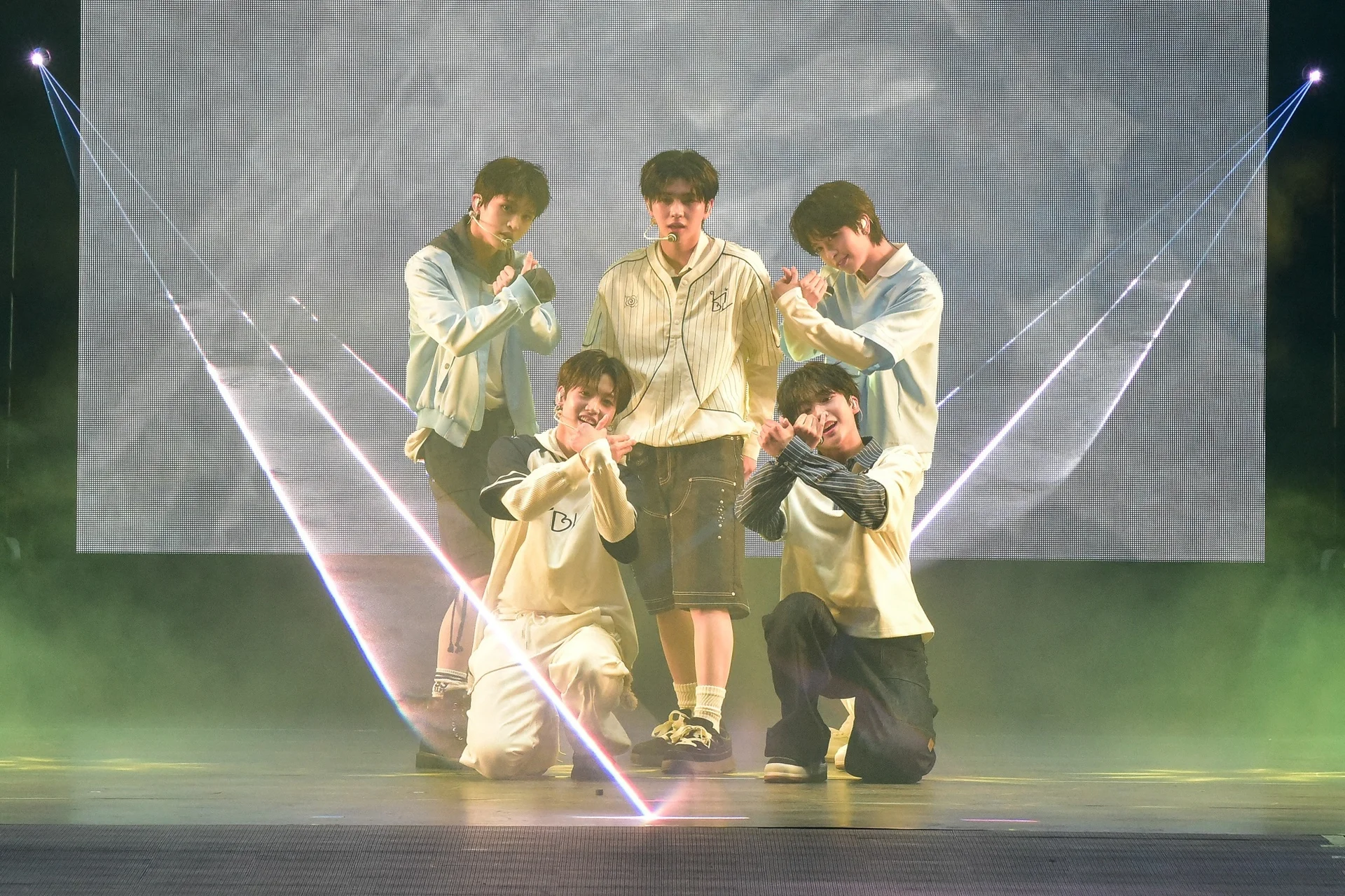 Integrantes do VIBY posando juntos no palco sob luzes coloridas