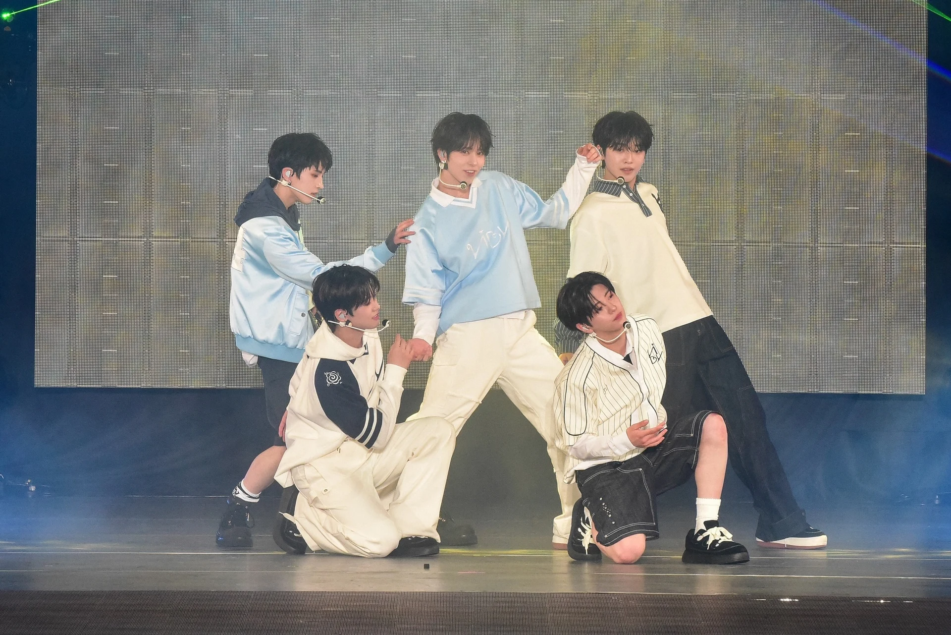 VIBY realizando um movimento de dança sincronizado no palco com roupas combinando