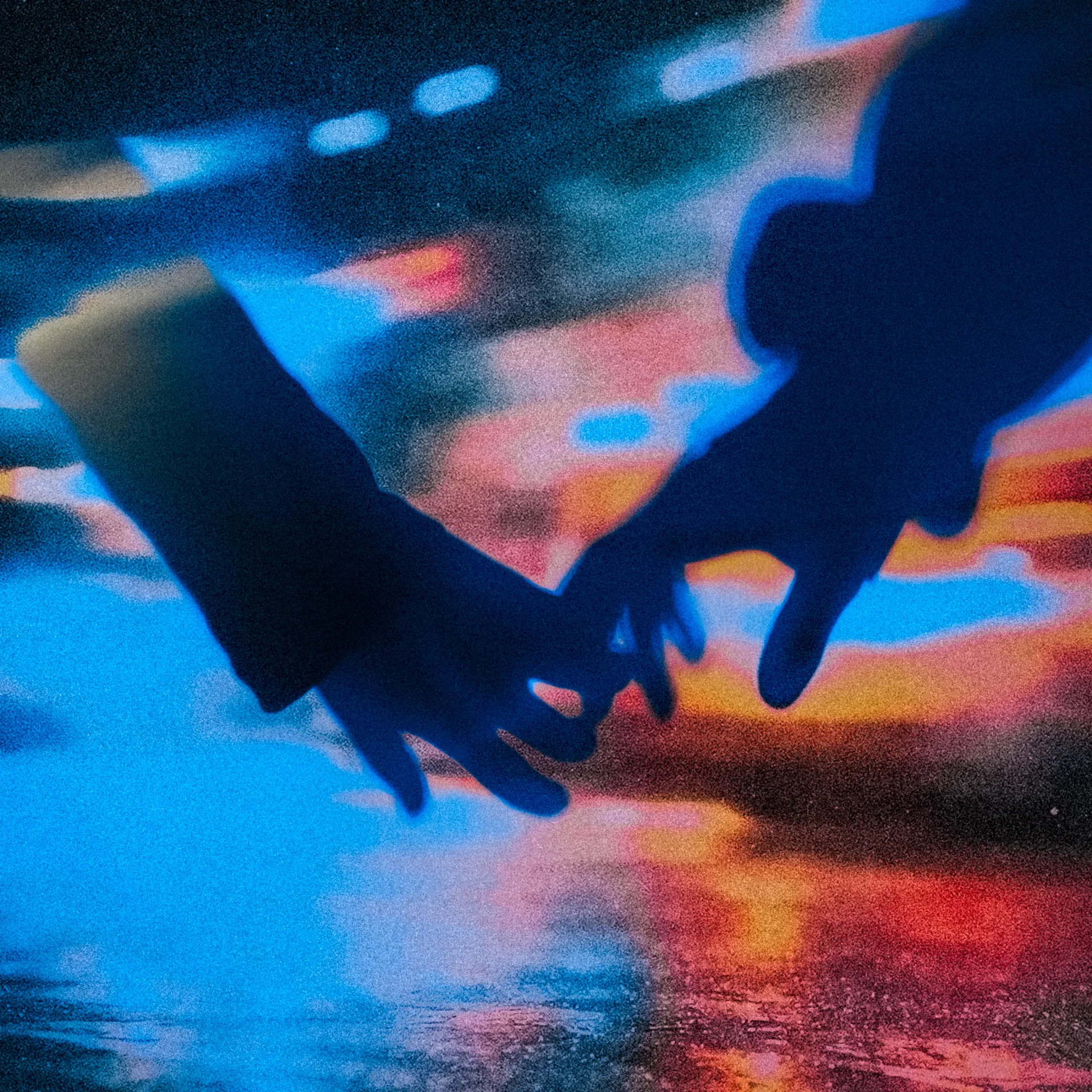 Sziluettezett kezek egymás felé nyúlnak egy elmosódott neonos városképi háttér előtt