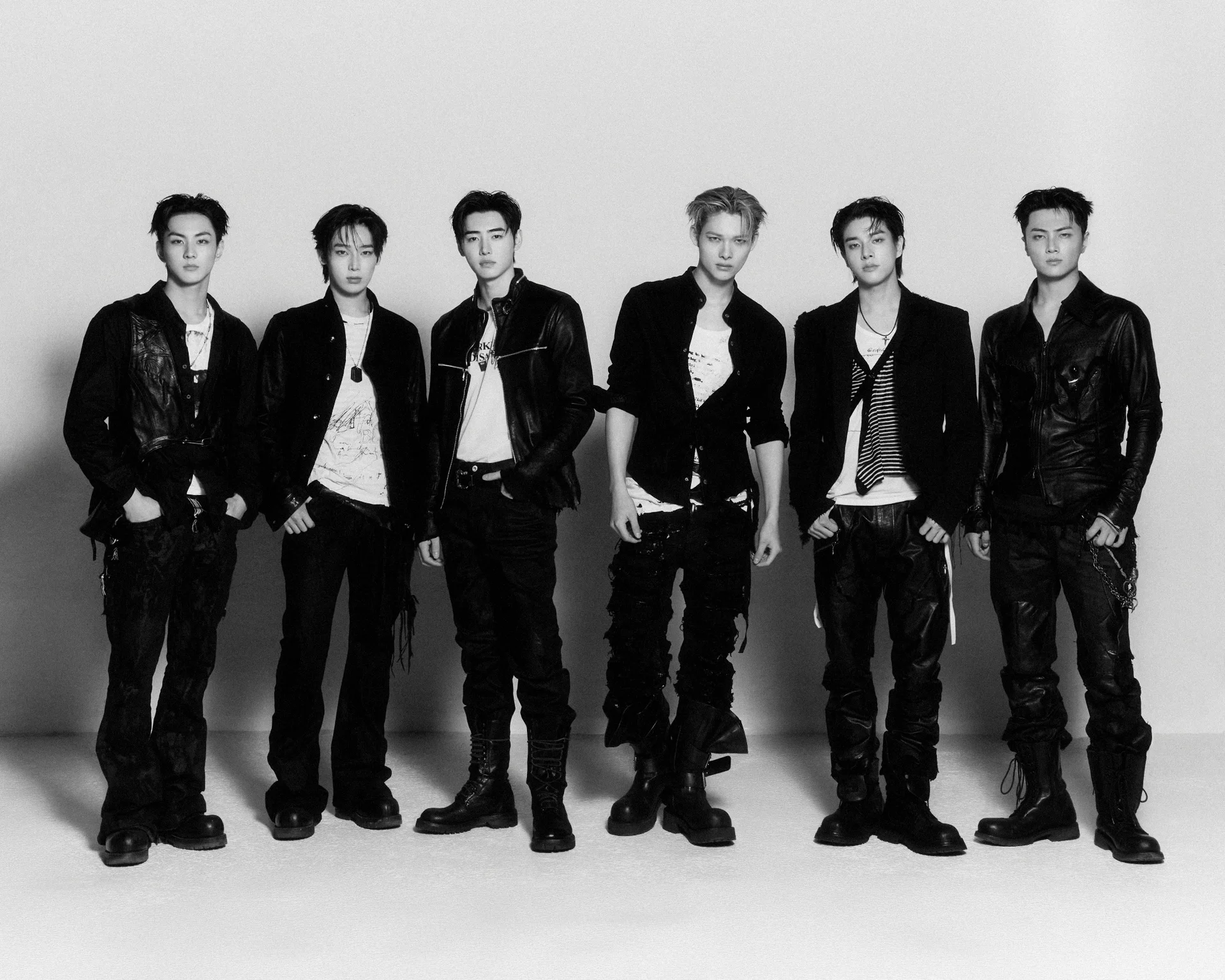 Membri degli ENHYPEN in posa insieme con abiti neri