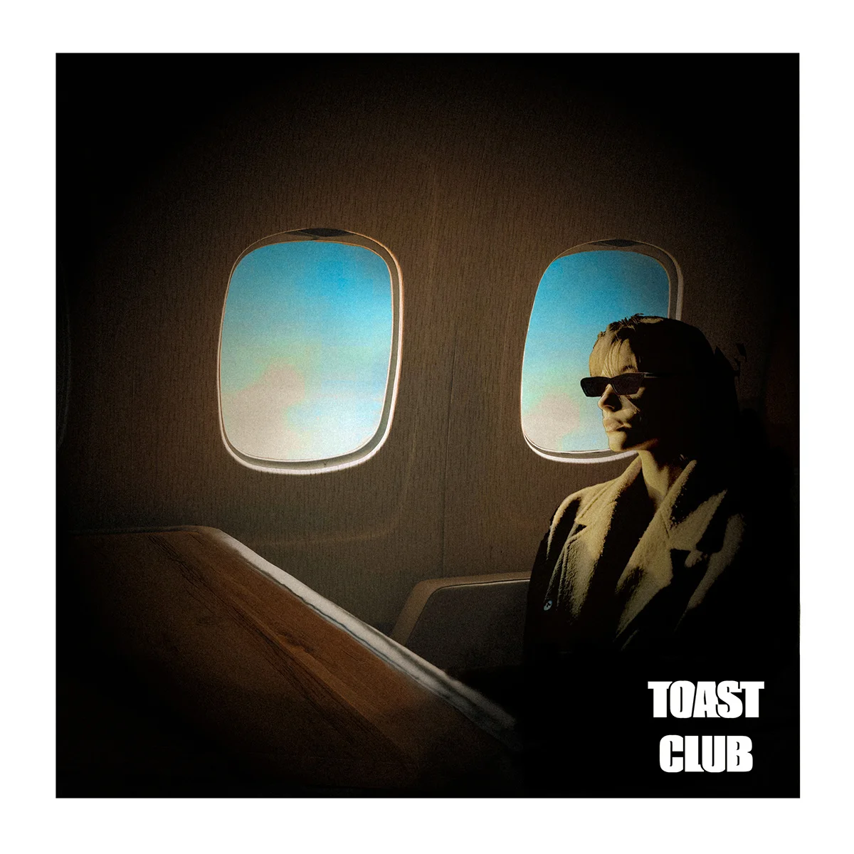 Silhouetted person seated on airplane with TOAST CLUB logo