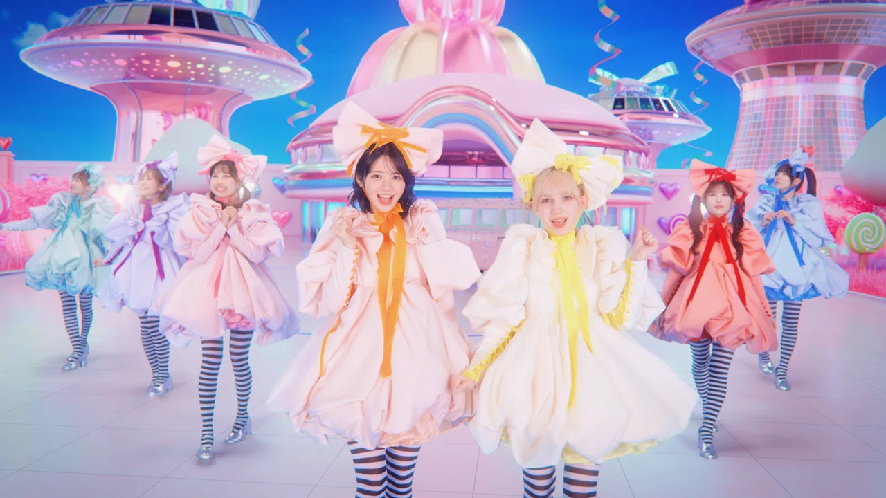 Członkinie FRUITS ZIPPER w pastelowych kostiumach na kolorowej, futurystycznej scenie.