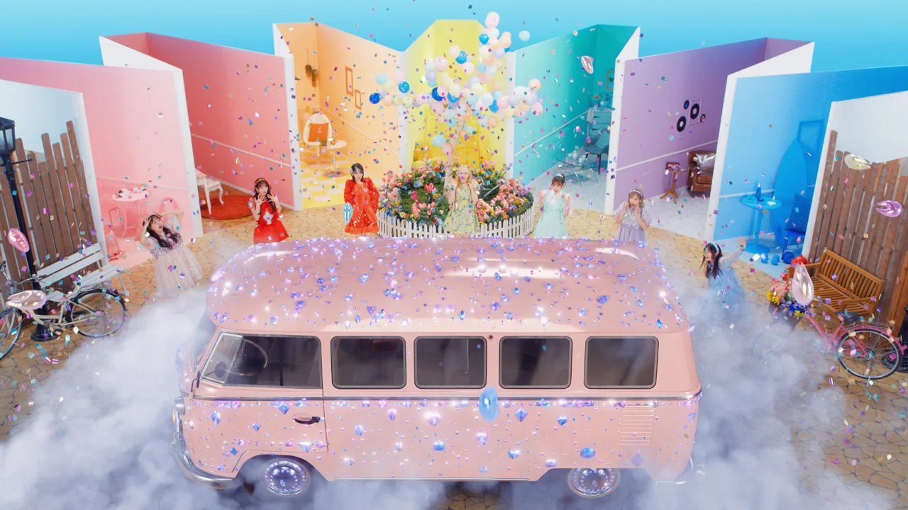 FRUITS ZIPPER w kolorowych strojach z konfetti i różową furgonetką na żywiołowej scenie.