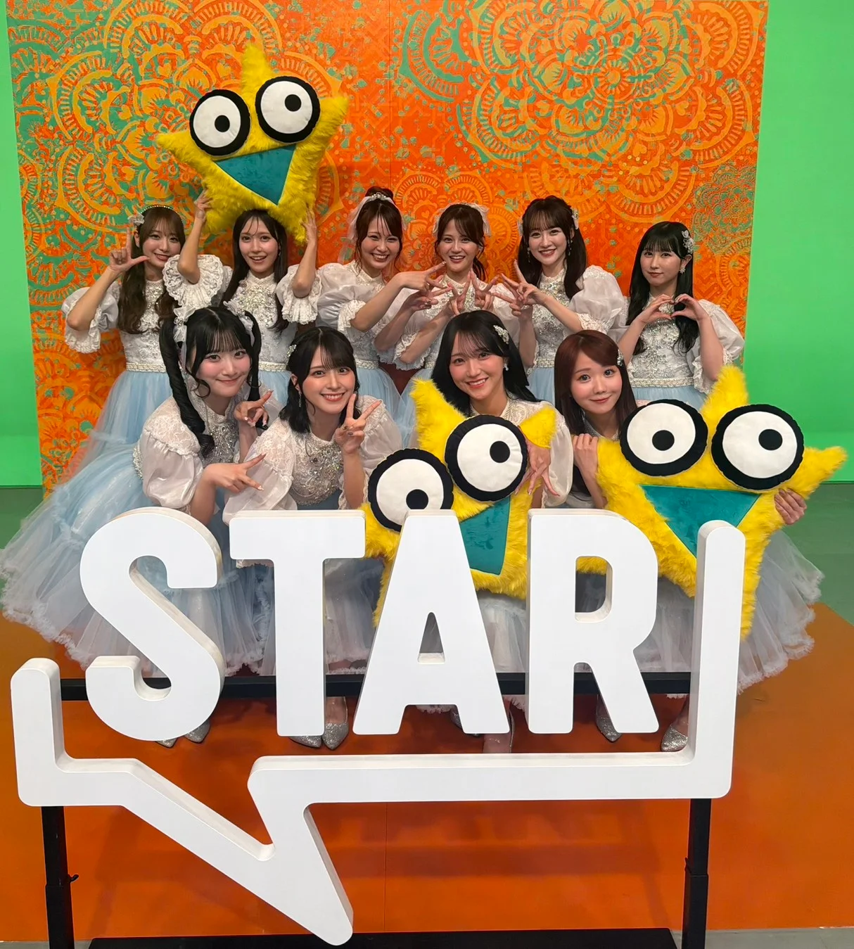 =LOVE members in blue costumes behind a STAR sign