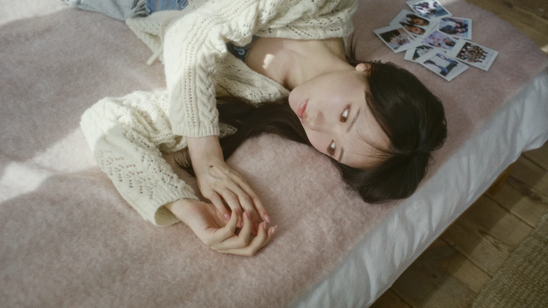 Ishida lying on a bed surrounded by photographs