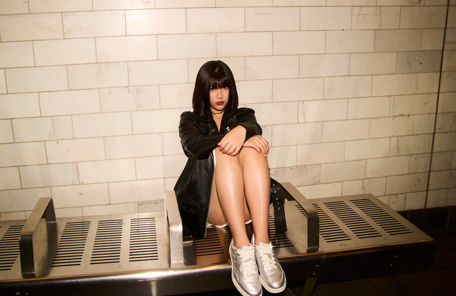 Maya seated on a bench in a subway setting