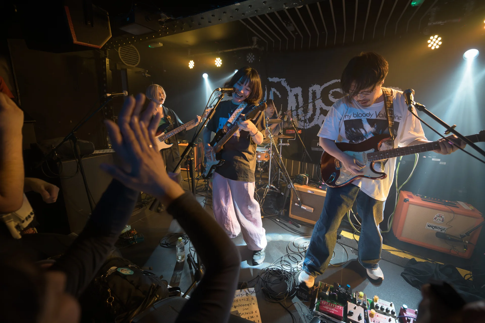 Japanese band performing with audience in dimly lit venue