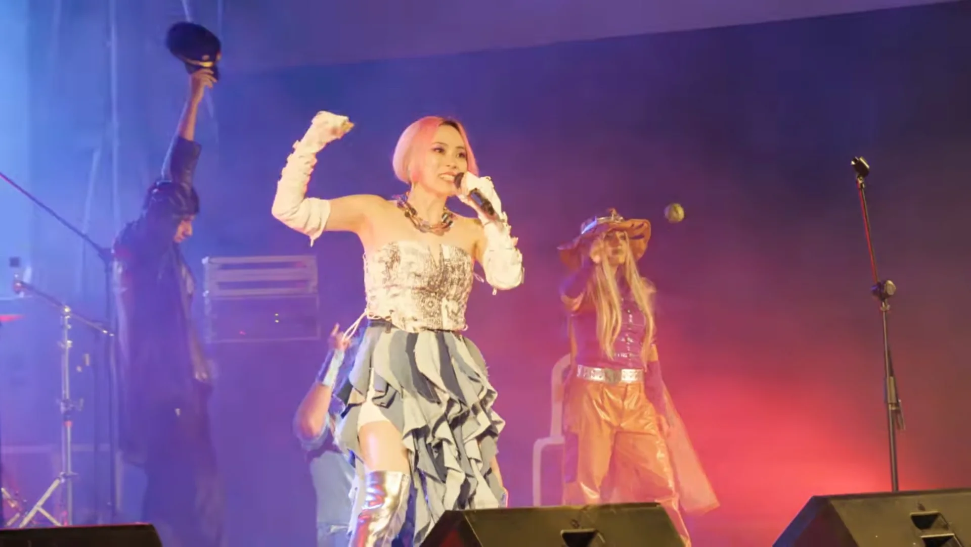 Shihori performing energetically on stage with dancers