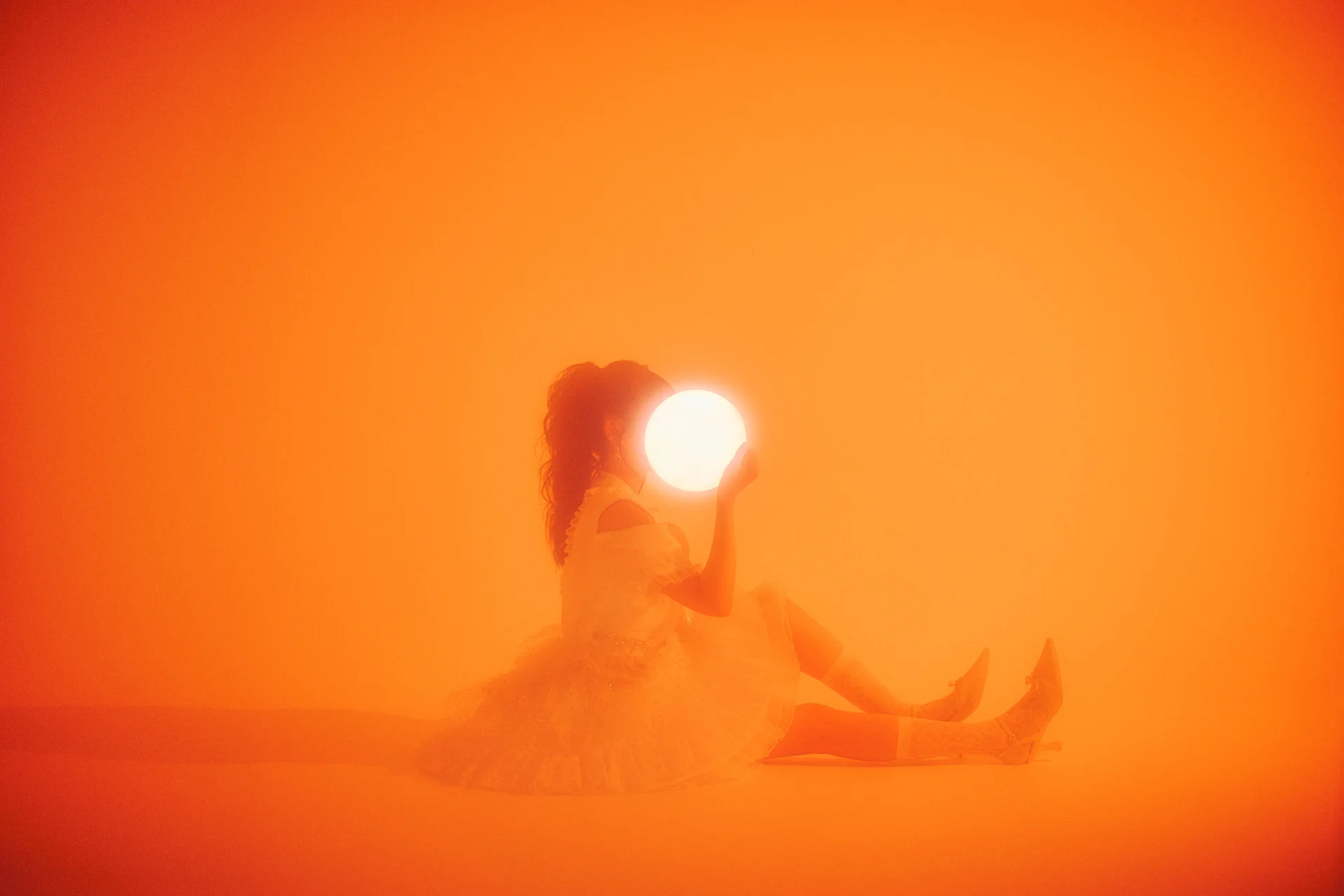 Silhouette of a person holding a glowing orb against an orange background