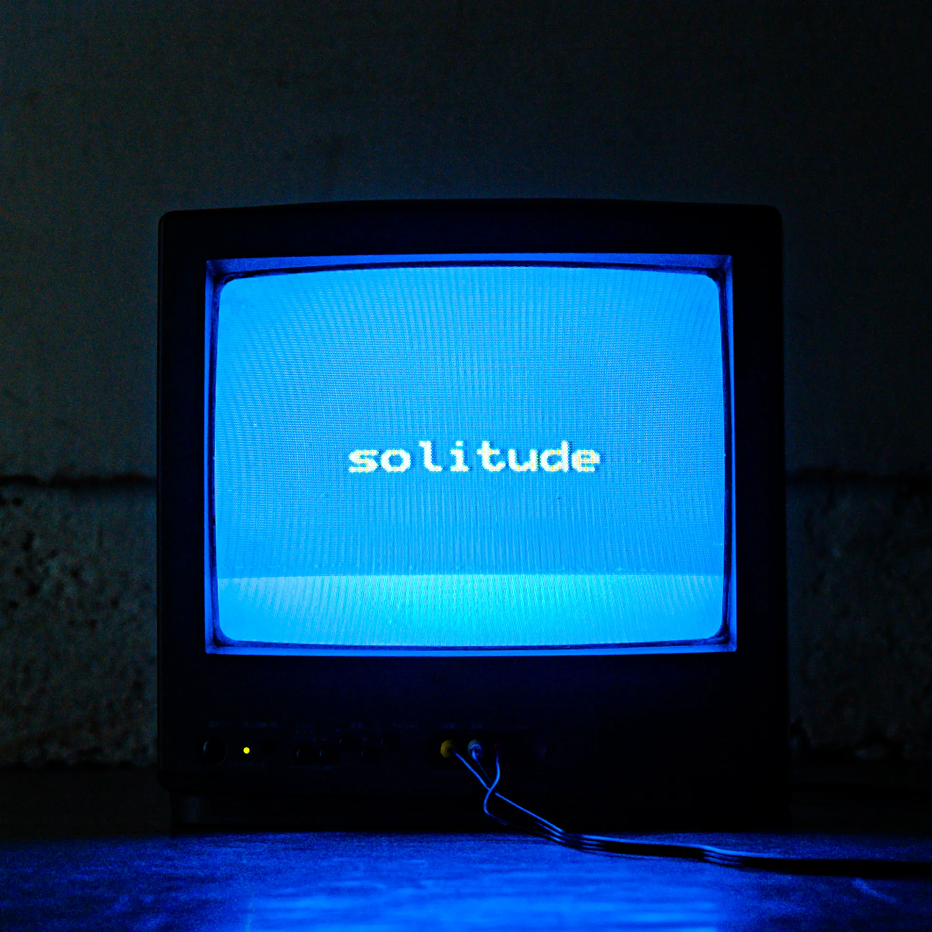 Vecs CRT televizors, kas tumšā telpā parāda vārdu solitude ekrānā