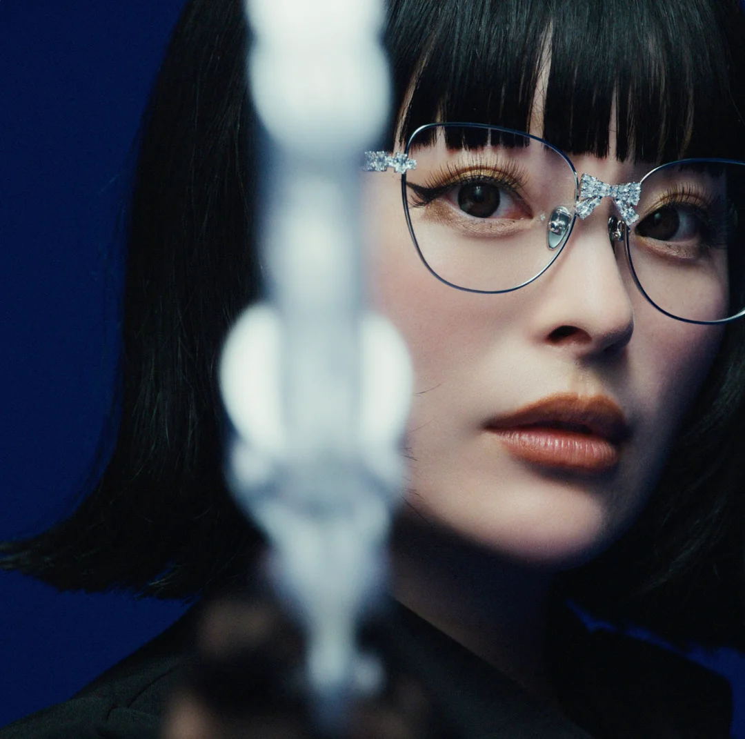 Kyary Pamyu Pamyu mit dunklen Haaren und Brille, ein stabähnliches Objekt haltend