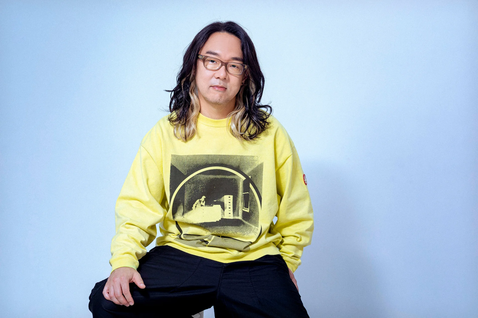 Tomoya Ohtani sėdintis geltona sportine liemene