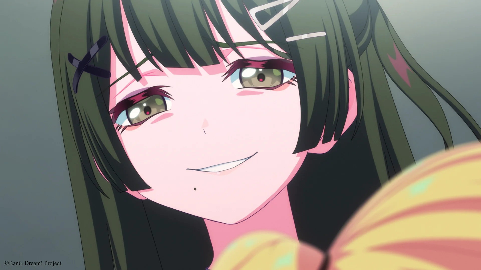 Anime postava s dlouhými tmavými vlasy a sponkami do vlasů se jemně usmívá.