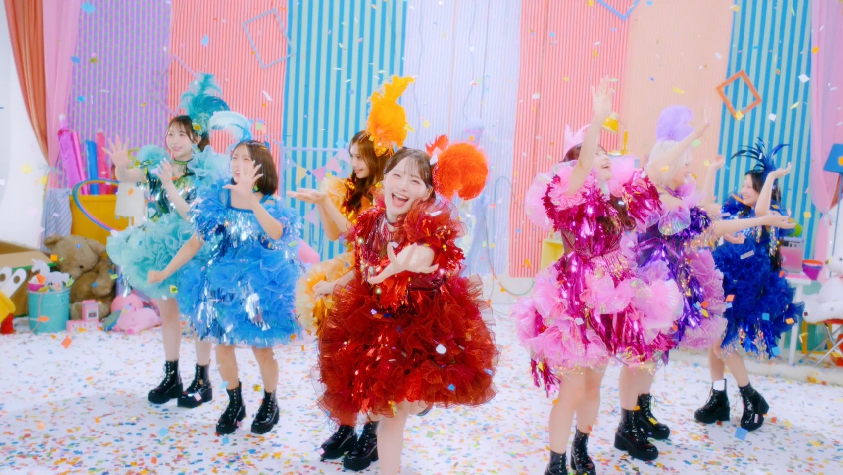 CANDY TUNE performing in colorful feathered costumes on a confetti-covered floor
