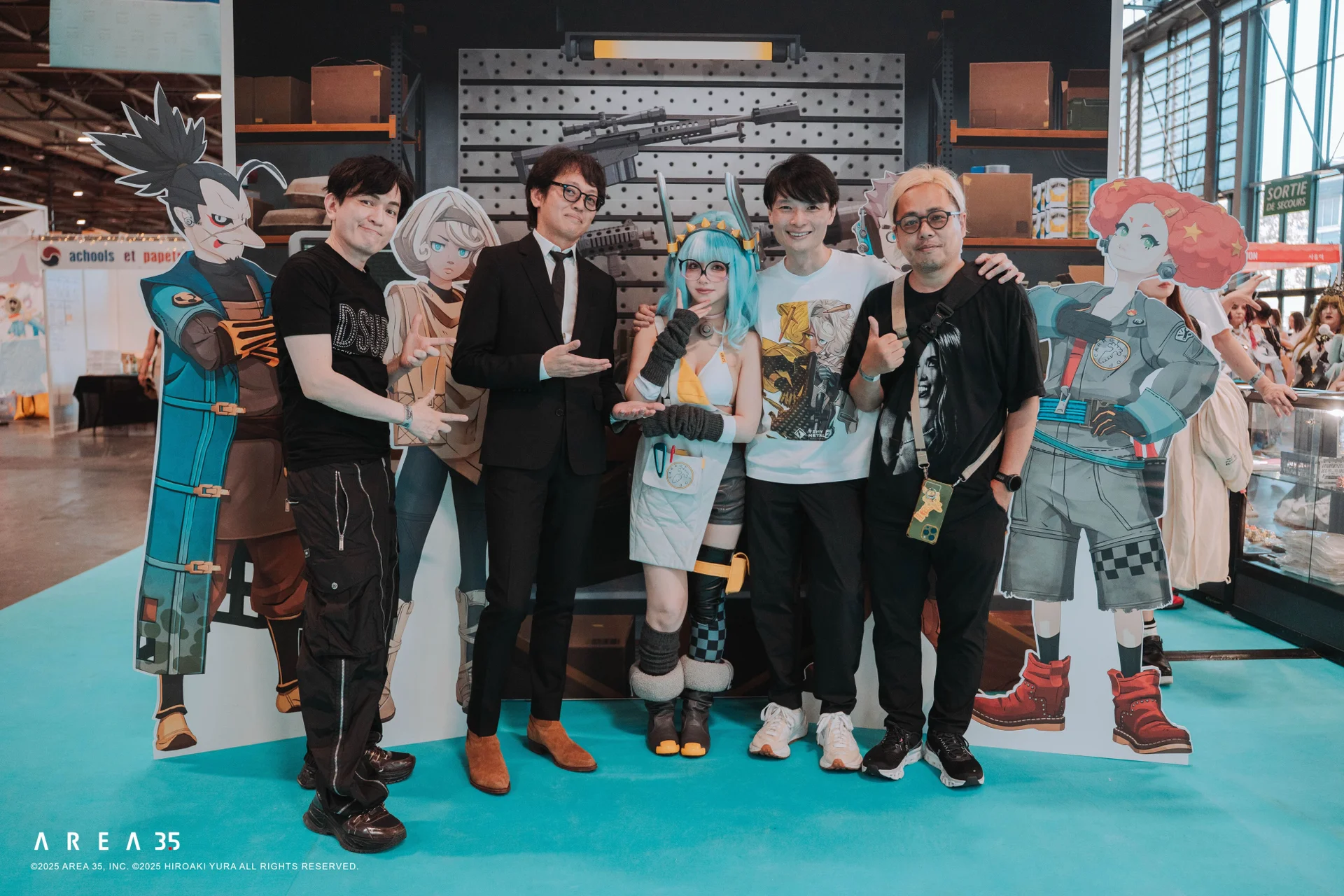 Group posing at Tiny Metal booth with character cutouts