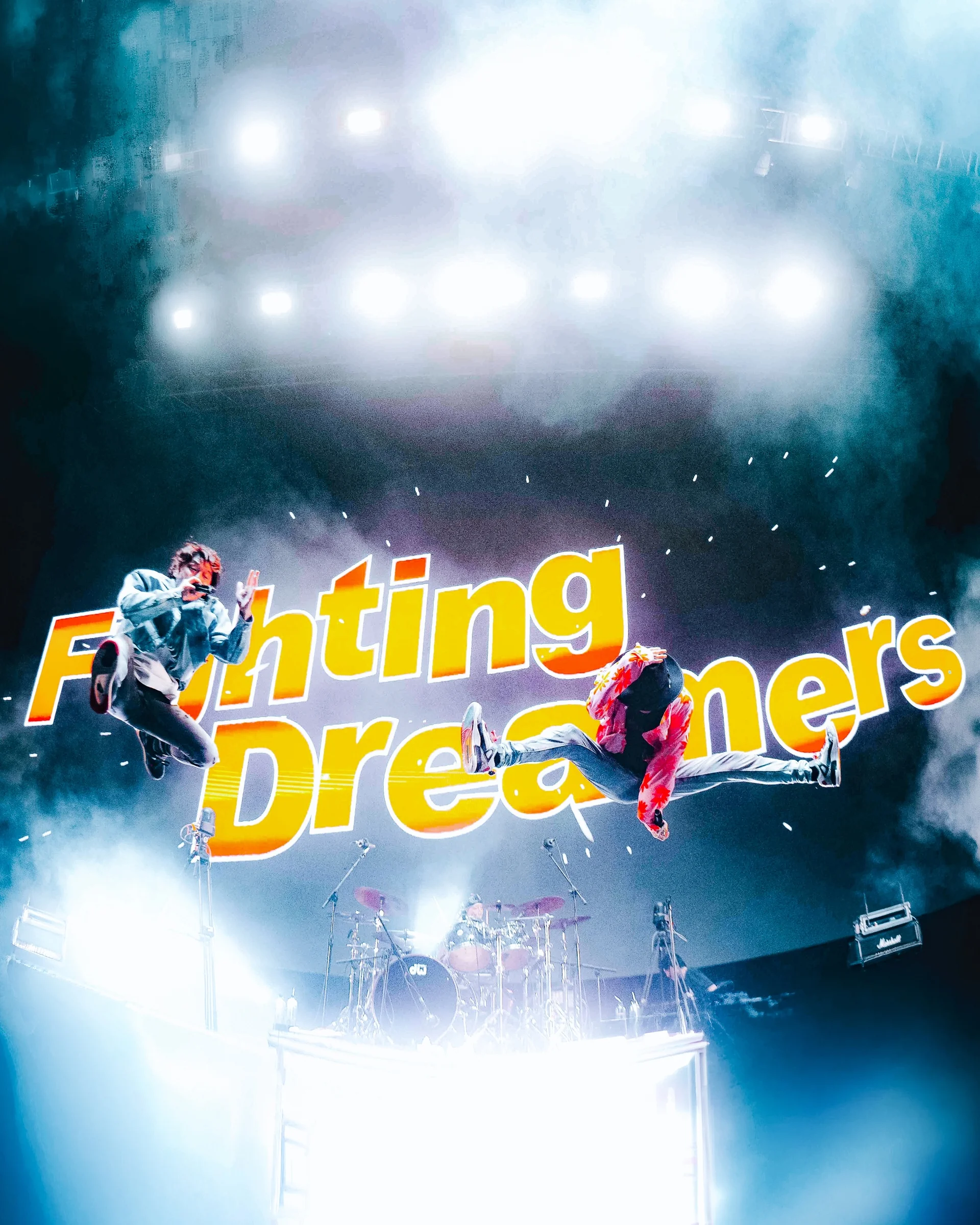 Two <a href="https://onlyhit.us/music/artist/FLOW" target="_blank">FLOW</a> performers mid-air on stage with drums