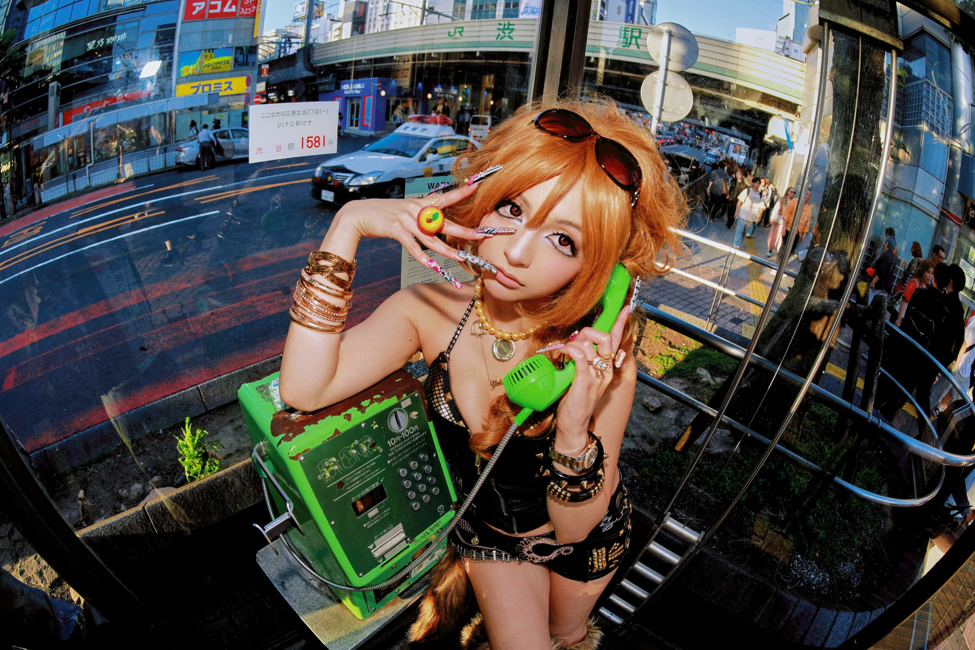 Yukipoyo poserer med en grønn offentlig telefon i Shibuya