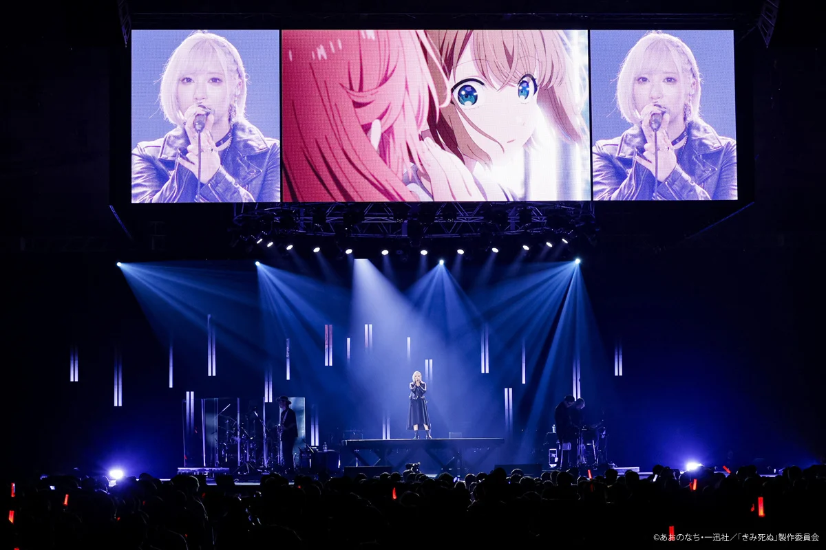 ReoNa on stage with anime visuals displayed on large screens